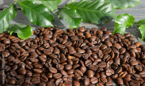 Coffee beans on a wooden background with leaves of a coffee tree with spaces for text. flat layout