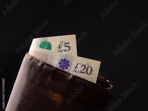 5 and 20 pounds bill, bank notes in the leather wallet isolated on the black background