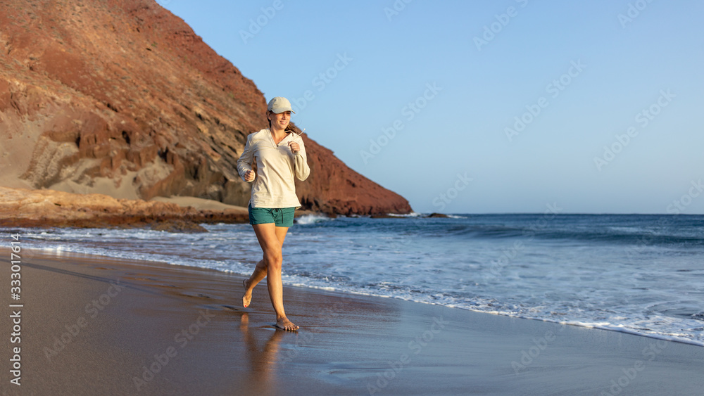Young woman running on La Tejita beach, Tenerife , Spain