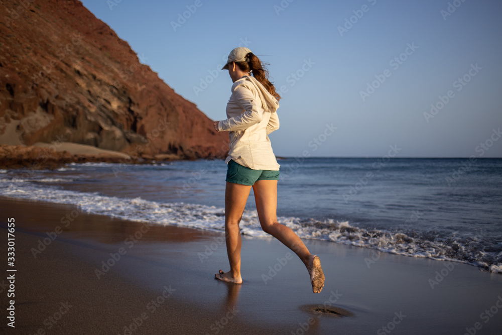 Young woman running on La Tejita beach, Tenerife , Spain