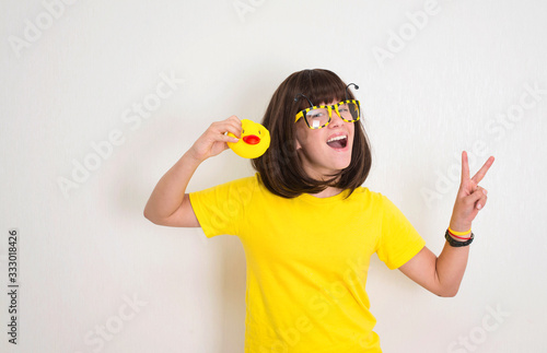 Teen girl in funny glasses with duck face and yellow rubber duck having fun. Party props, photo booth and people concept.