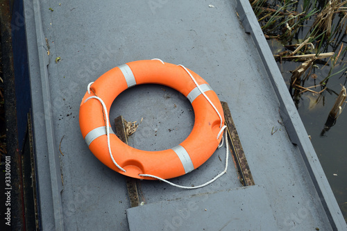 Modern Orange Plastic Life Preserver with Rop on Top of Canal Barge  photo