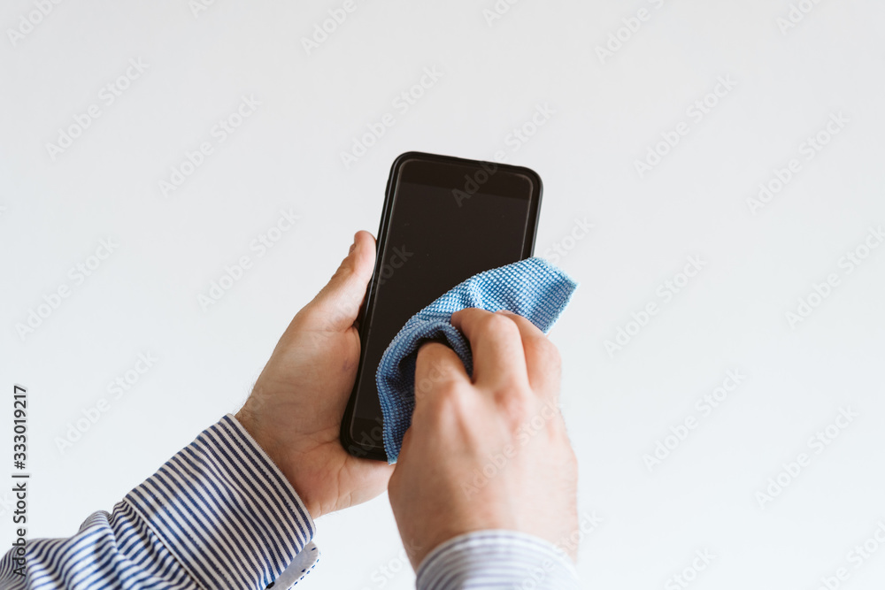 close up view of a man cleaning mobile phone with disinfectant. Hygiene and coronavirus covid-19 concept close up view of a man cleaning mobile phone with disinfectant. Hygiene and coronavirus covid-19 concept