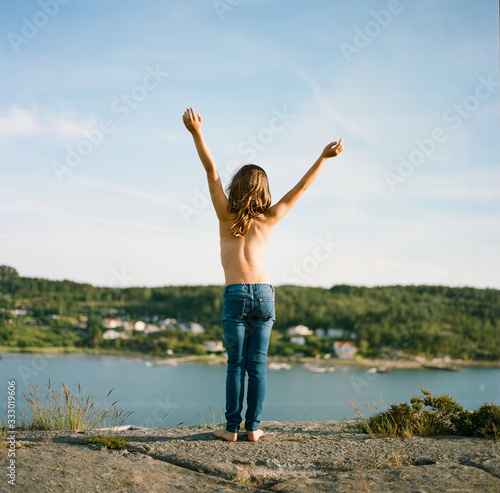 Young girl wearing jeans and no shirt with her back facing the camera photo
