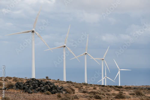 Many wind turbines on high hill among stones. photo