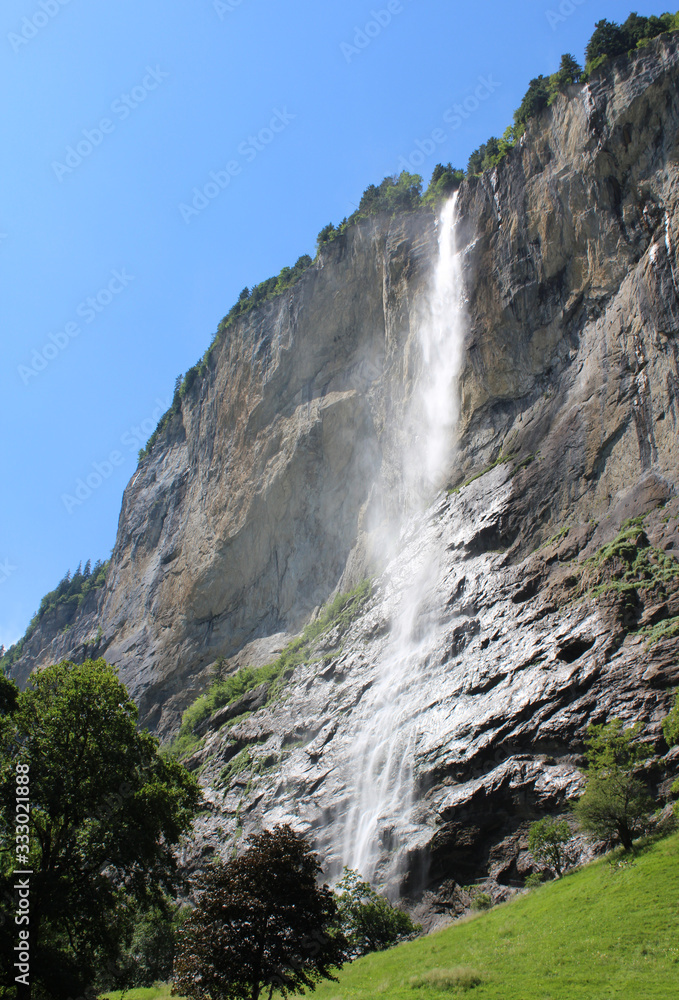 View of the spectacular 300m Staubbach Waterfall in Lauterbrunnen, in the Bernese Oberland in Switzerland, in summer with blue sky. View of the spectacular 300m Staubbach Waterfall in Lauterbrunnen, in the Bernese Oberland in Switzerland, in summer with blue sky.