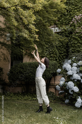 young woman reaching up to a tree in beautiful yard