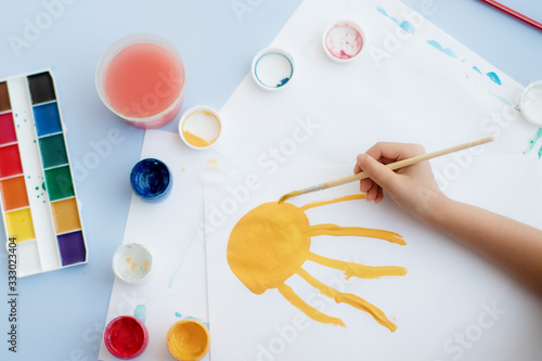 a child's hand with a paint brush draws at a table in a kindergarten or in a development center