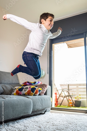 Fototapeta Naklejka Na Ścianę i Meble -  Funny kid jumping off the couch