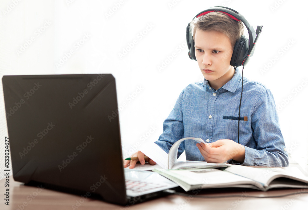 Distance learning in quarantine. A boy in headphones in front of a computer does his homework. Distance learning in quarantine. A boy in headphones in front of a computer does his homework.