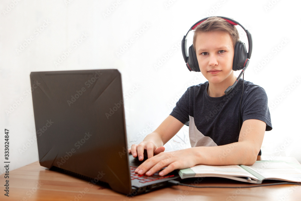 Distance learning in quarantine. A boy in headphones in front of a computer does his homework. Distance learning in quarantine. A boy in headphones in front of a computer does his homework.