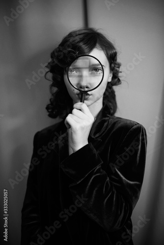Portrait of a girl in the velvet jacket with magnifier