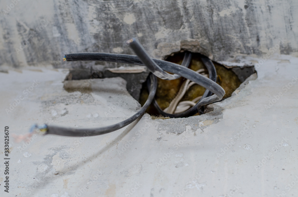 repair in the apartment. wires stick out of a hole in a concrete wall. The owner of the house is waiting for an electrician.