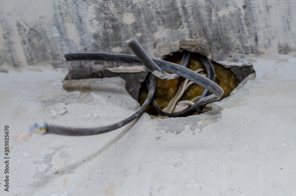 repair in the apartment. wires stick out of a hole in a concrete wall. The owner of the house is waiting for an electrician. repair in the apartment. wires stick out of a hole in a concrete wall. The owner of the house is waiting for an electrician.
