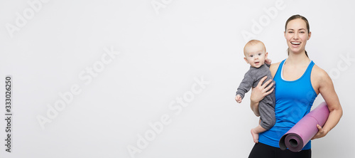 Smiling fit yoga mom posing with her happy baby with copy space 