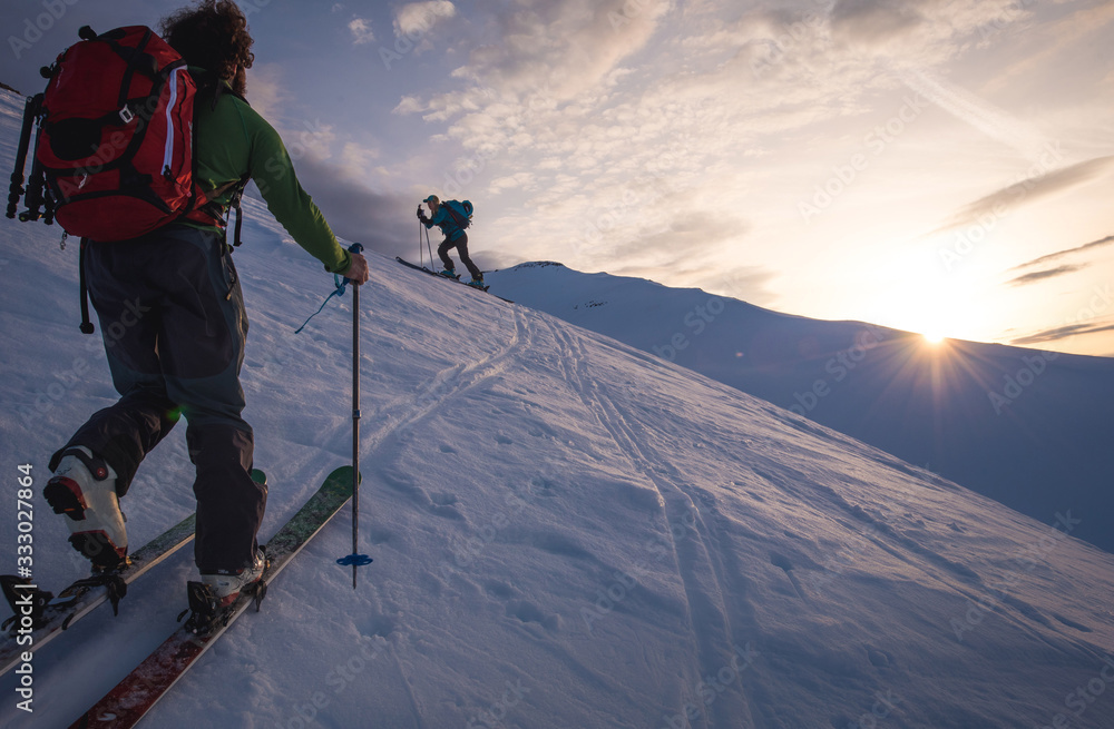 Two people backcountry skiing in Iceland at sunrise Two people backcountry skiing in Iceland at sunrise