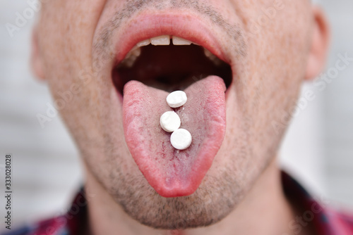 Cut view and close up of man with opened mouth with three white pills on tongue. Drugs addicted or pain relief from sickness. Show it on camera.