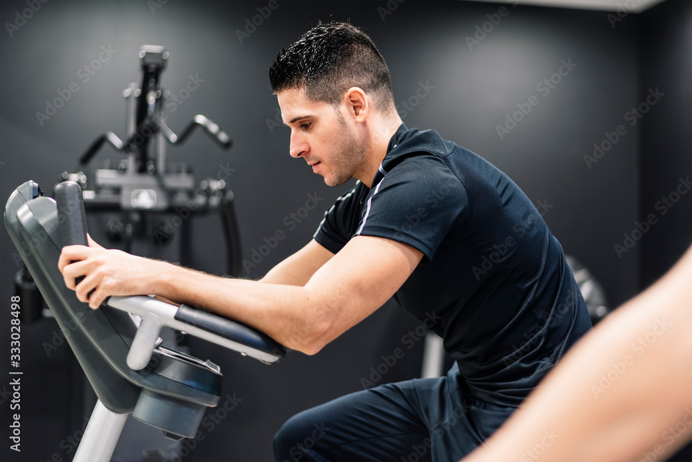 young man at the gym on a bicycle young man at the gym on a bicycle
