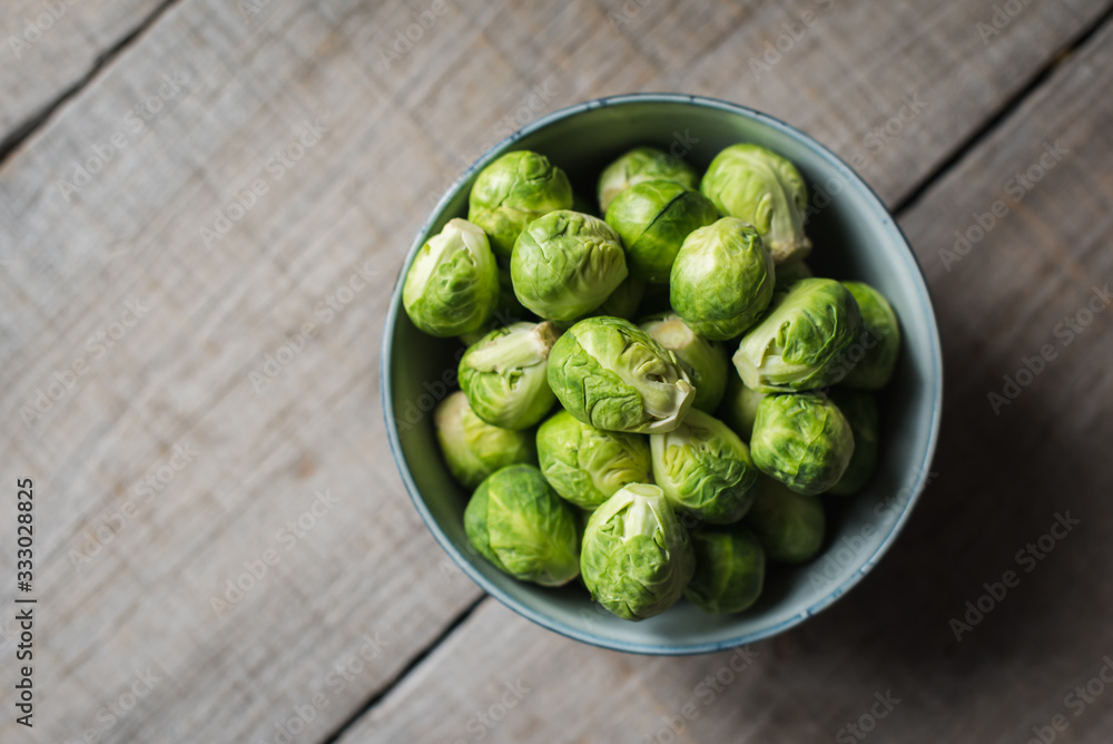 Overhead view of bowl of Brussels sprouts on wooden background. Overhead view of bowl of Brussels sprouts on wooden background.