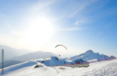 paragliding over a snowy mountain landscape at a ski resort