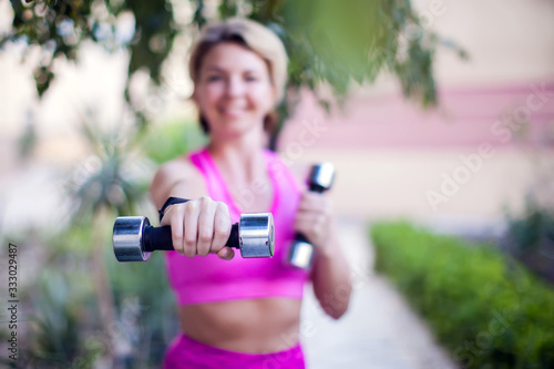 Woman doing exercise with dumbbells outdoor. People, healthcare and lifestyle concept.