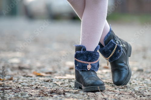 Closeup of child girl feet in pink leggings and fashionable autumn shoes standing outdoors in sunny fall weather.