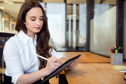 Slika na platnu Young business professional at office workspace sitting at desk writing on table