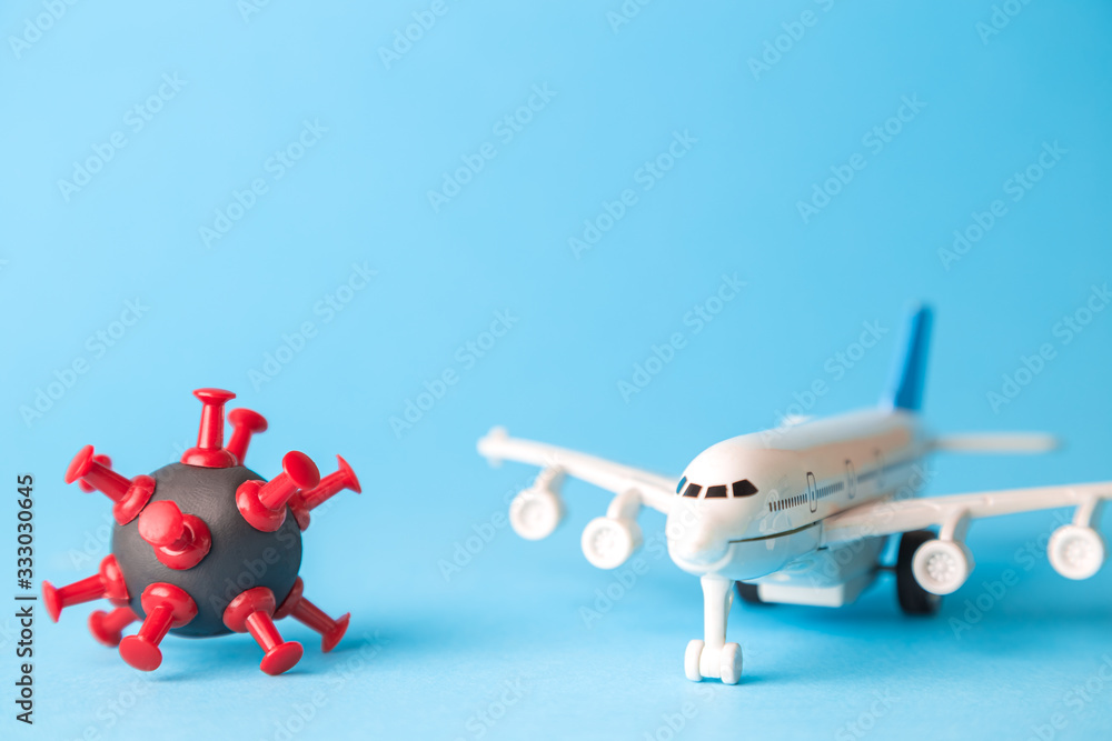 Travel restrictions concept made of coronavirus cell and airplane toy on pastel blue background. - obrazy, fototapety, plakaty 