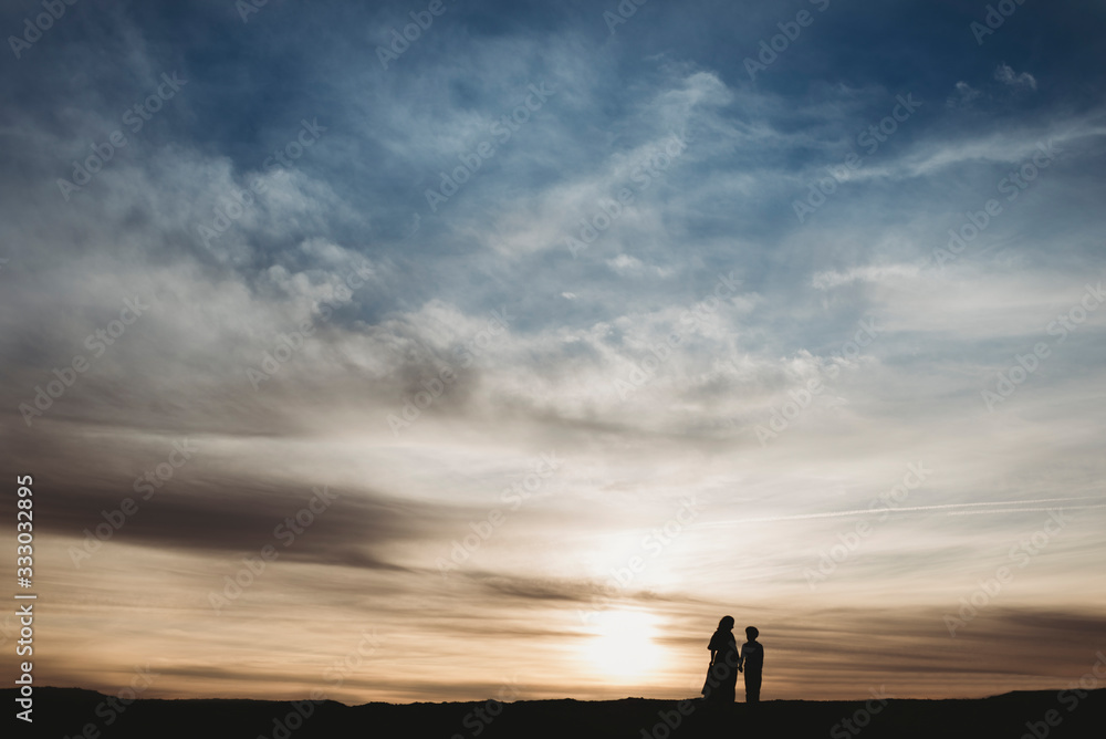 Silhouette of young mother and school-aged son walking at beach Silhouette of young mother and school-aged son walking at beach
