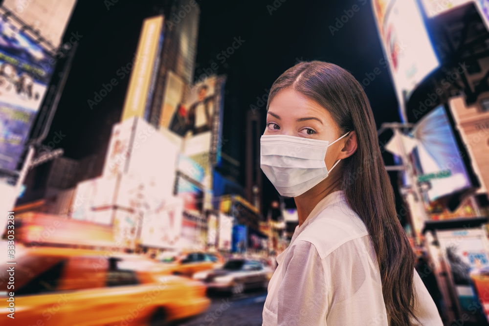 New York City COVID-19 Coronavirus cases. NYC Quarantine travel ban asian woman wearing face mask walking at night in Times Square. Corona virus .