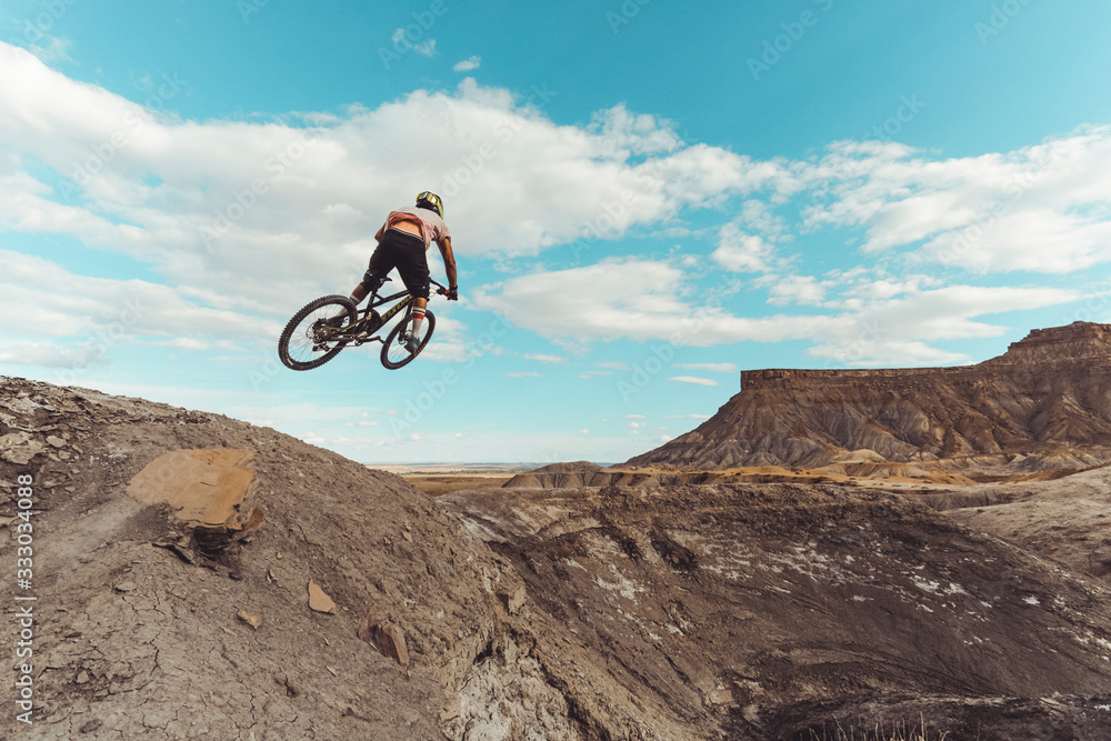 Male jumping with mountain bike in front of dramatic mountains Male jumping with mountain bike in front of dramatic mountains