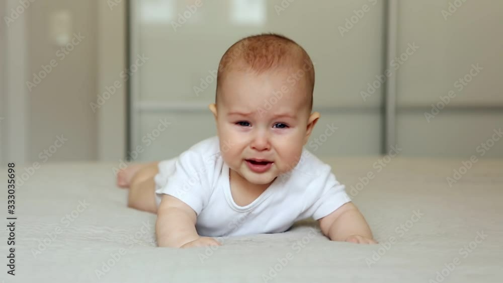 Baby lying on bed looking at the camera and crying Baby lying on bed looking at the camera and crying