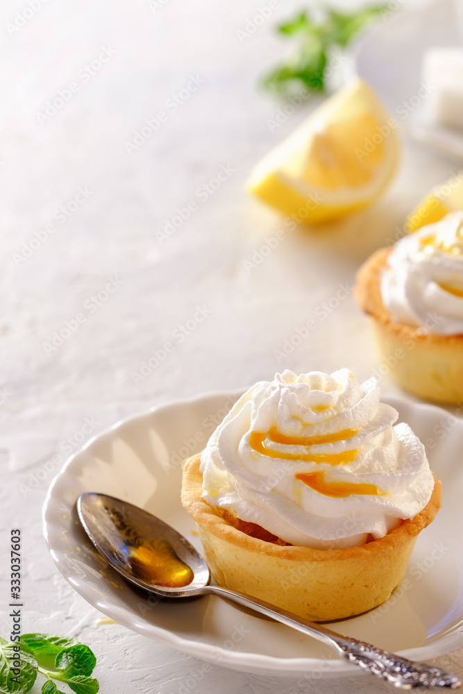 Tartlets with lemon kurd and italian meringue on a white plate Tartlets with lemon kurd and italian meringue on a white plate