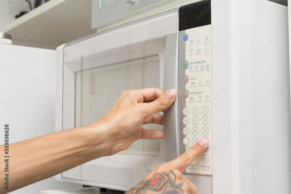 Close up of a hand using a microwave oven in the kitchen at home Close up of a hand using a microwave oven in the kitchen at home