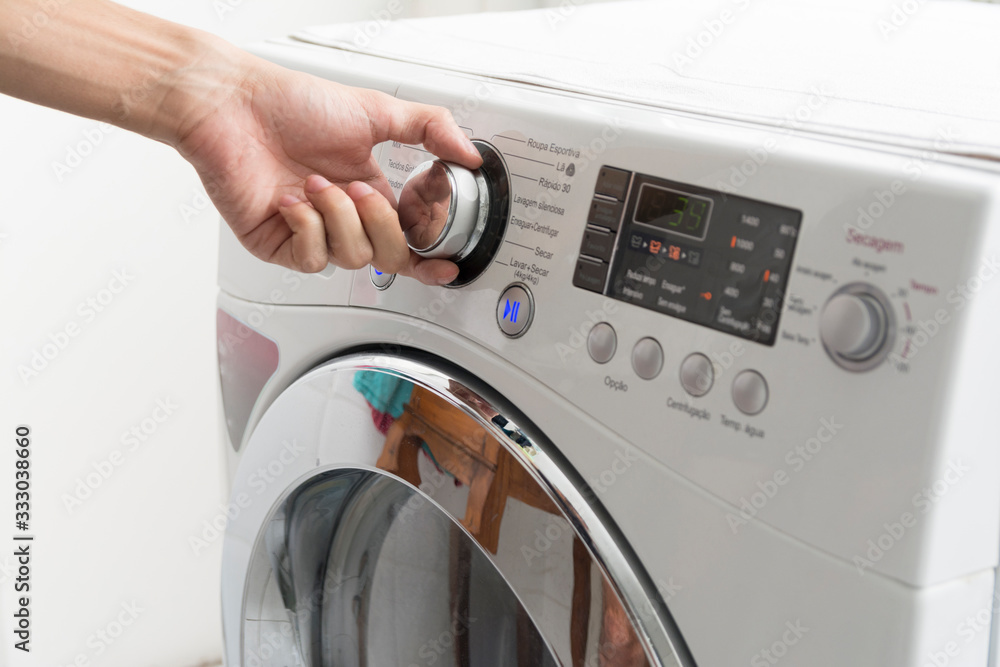 Male hand operating a washing machine at home Male hand operating a washing machine at home