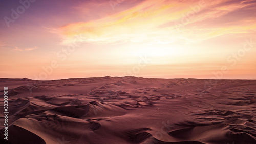 Martian landscape view of the dessert with sand dunes during the orange - purple sunset in Peru. 