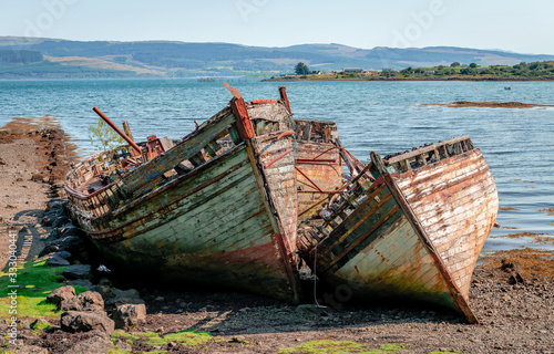 Beautiful seascape with three semi-destroyed old fishing boat in the beach and the Sound of Mull in the background. Isle of Mull  Scotland  August 2019.