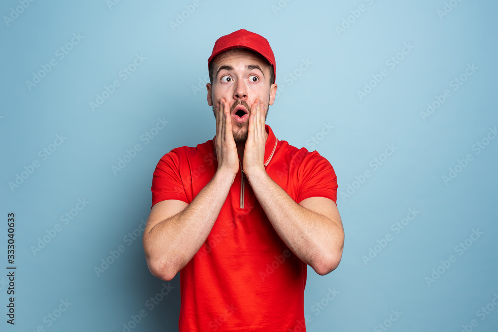 Courier with amazed and surprised expression face. Cyan background Courier with amazed and surprised expression face. Cyan background