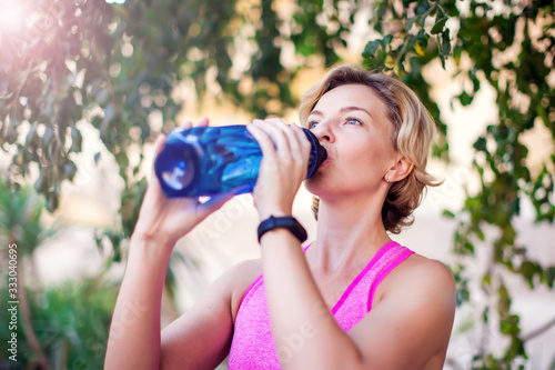 Woman drinking water after exercises outdoor. People, healthcare and lifestyle concept.