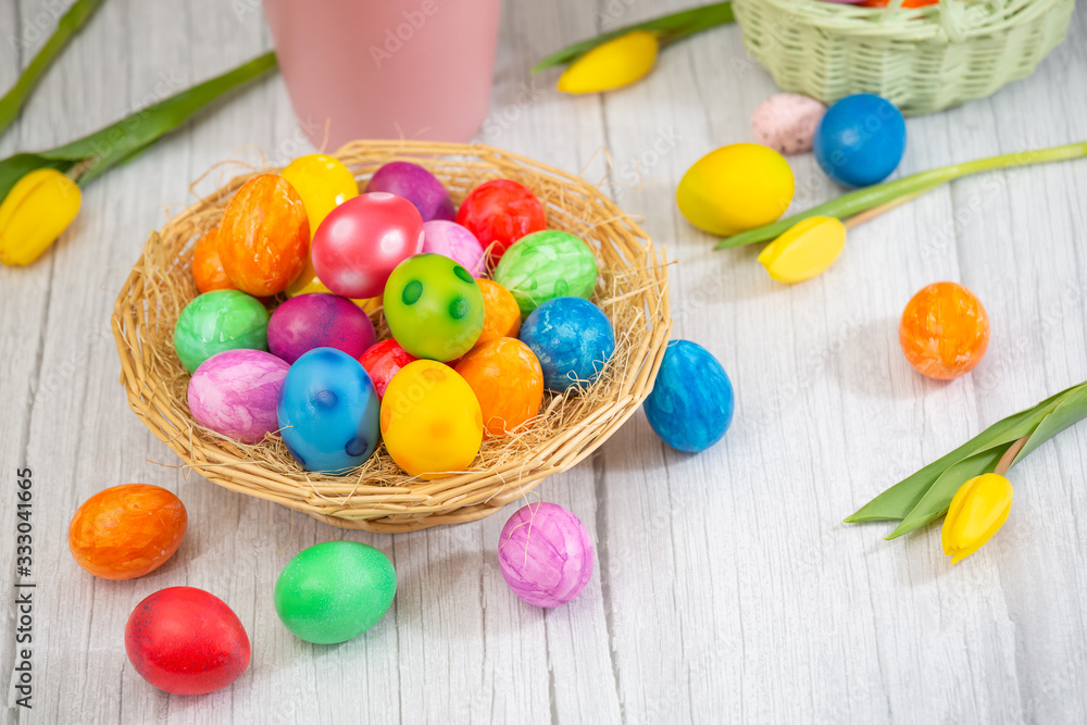 Beautiful group Easter eggs in the spring of easter day, red eggs, blue, purple and yellow in Wooden basket with tulips on the wood table background Beautiful group Easter eggs in the spring of easter day, red eggs, blue, purple and yellow in Wooden basket with tulips on the wood table background