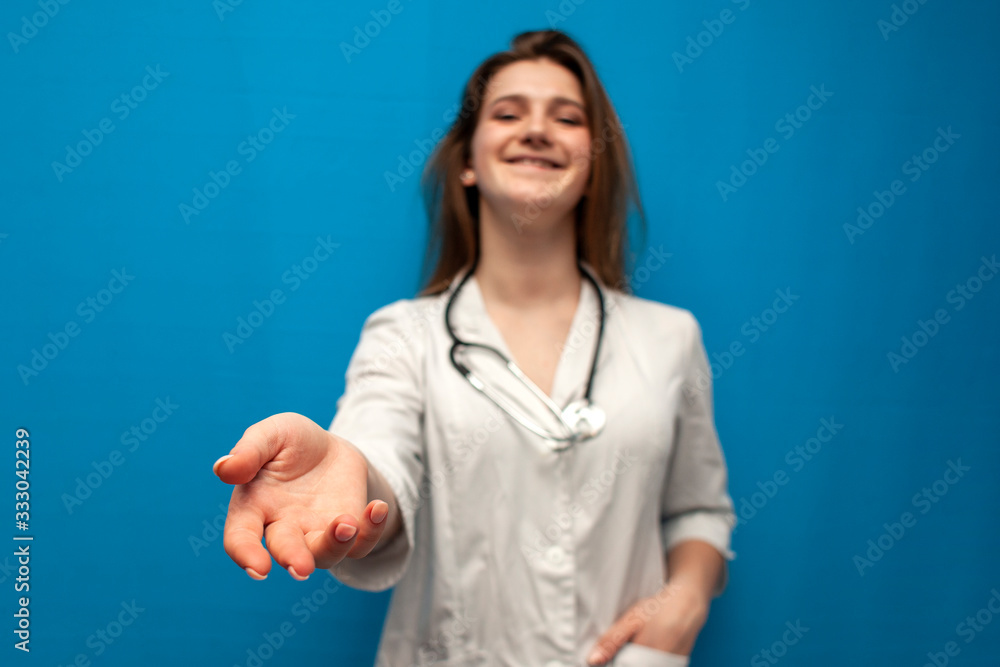 young cheerful girl nurse smiles and gives a helping hand, female doctor on a blue background young cheerful girl nurse smiles and gives a helping hand, female doctor on a blue background