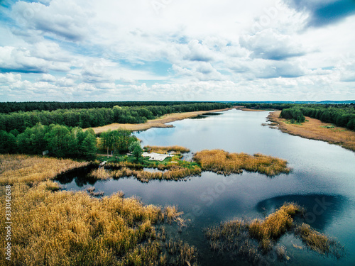 A beautiful sunny view of the forest, fields and river from above with a drone. © osovik.igor
