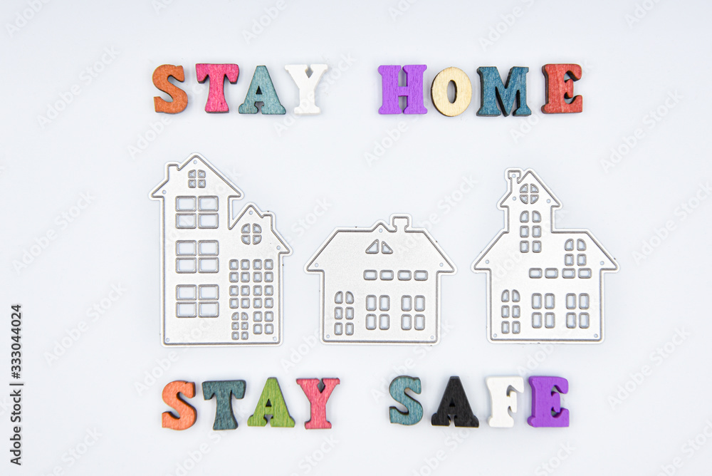 Words Stay home Stay safe made from wooden letters and three metalic houses, concept of self quarantine at home as preventative measure against corona virus Covid 19 outbreak.