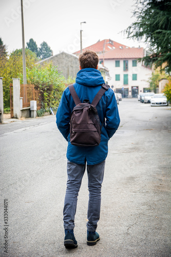 Teenage boy walking alone in street with backpack