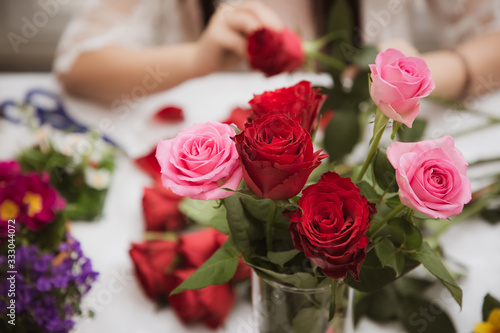 Woman Preparing to trim red and pink roses and beautiful flower arrangements in the home, flower arrangements with vase for gift-giving for Valentine's Day and Business in the family on the on table