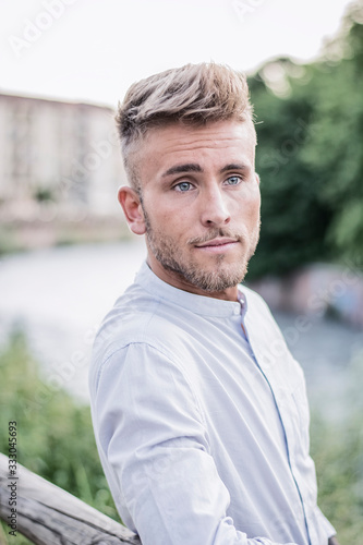 Blondish, blue eyed young man by river smiling