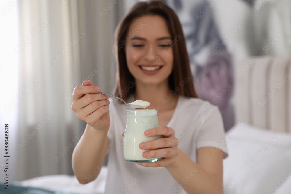 Young attractive woman with tasty yogurt in bedroom, focus on hands Young attractive woman with tasty yogurt in bedroom, focus on hands