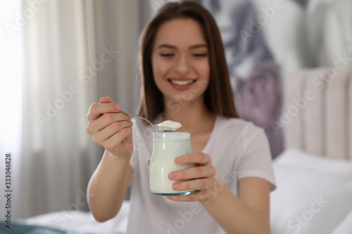 Young attractive woman with tasty yogurt in bedroom  focus on hands