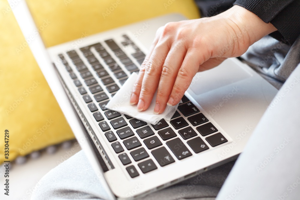 woman wiping laptop keyboard with disinfection wipes due to corona virus risk woman wiping laptop keyboard with disinfection wipes due to corona virus risk
