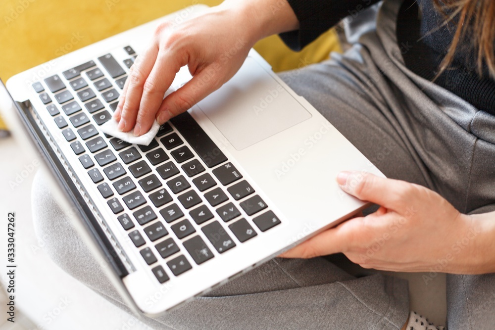 woman wiping laptop keyboard with disinfection wipes due to corona virus risk woman wiping laptop keyboard with disinfection wipes due to corona virus risk